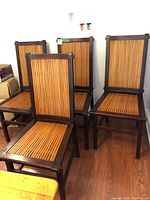 Set of four wood dining chairs with ribbed wood seats and backs shown together from an angle.