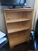 Front view of the wooden shelving unit showing the shelves and overall condition.
