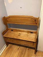 Front image of a wooden entry bench showing worn surface, water stains, and a hinged seat top with storage compartment beneath.