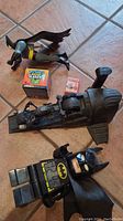 Photo showing Lego Batman bath toy, Mystery Tackle Box, small box of sticker bandages, wind-up Batmobile, and Lego Batman clock figure.