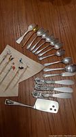 View of collection spoons, swizzle sticks, and a cheese cutter on a wooden table