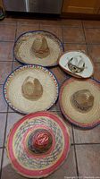 Photo showing the five hats on a tiled floor, highlighting a variety of woven colors and styles.