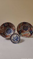 Photo showing two unmarked Japanese Imari bowls and one small blue and white English porcelain plate