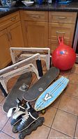 Mini stick hockey nets, three skateboards, red bouncy ball, and pair of black rollerblades on kitchen floor.