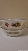 Front view of the stacked round Pyrex vegetable pattern dish and oblong Fire King casserole dish.