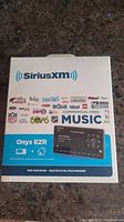 Front view of the SiriusXM Onyx EZR radio home kit box showing product image and SiriusXM branding.