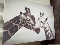 Close-up photo of one canvas showing two giraffes touching noses on a beige background.