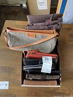 Box containing assorted clutch purses in various colors and materials including tan woven, brown, black, and red.