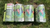 Four Coleman self-inflating sleep pads in original packaging shown lying on grass.
