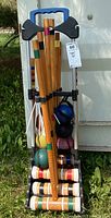 Front view of croquet set on metal cart with mallets, balls, and wickets visible.