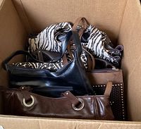 Top view of a cardboard box holding five handbags with varied patterns and materials.