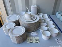 Overview of stacked dinner plates, salad plates, dessert plates, teacups, creamer, serving bowl and coffee pot on table