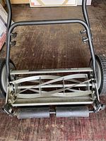 Front view of the reel blades, frame, and handle bar of the manual lawn mower showing cutting reel and roller.