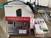 Lot showing Netgear N600 Wireless Dual Band Gigabit Router box, VideoSecu Flat Panel Swing Arm Mount box, and multiple cable packages including Philips HDMI and USB cables.