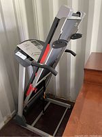 Folded treadmill upright showing digital console, handlebars and folded deck
