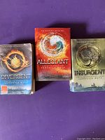 Photo of the three Divergent Trilogy books with covers visible: Divergent, Allegiant, Insurgent showing wear and tear.