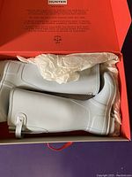 Hunter Original women's rain boots in white, neatly packed inside the original box with tissue paper wrapping, showing the full boot profile.