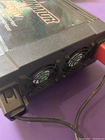 Close-up image showing two cooling fans on one side of the Motomaster Eliminator 2000 watt digital power inverter with connected cables.