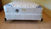 Front view of Searsopedic Evolution mattress and box spring on metal frame with casters, showing mattress labels and fabric details.