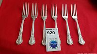 Six forks arranged on red background with auction label