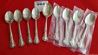 Nine spoons arranged on red background, four in packaging on right, five unwrapped on left