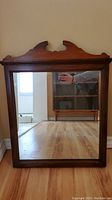 Front view of the rectangular wood framed mirror showing the reflective glass surface and dark wood frame.