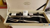 Two-piece carving set including carving knife and fork in original cream-colored hard case with black velvet lining, showing Gendis Super Stainless logo on the interior lid.