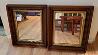 Pair of matching framed mirrors placed side by side on floor showing wood and gold ornate frames
