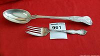 Full view of the 12-inch silverplate stuffing spoon and Holmes & Edwards serving fork showing their overall design and condition on a red background.