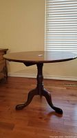 Full view of the round wooden table showing round top and pedestal base