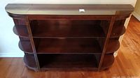 Front view of the wood shelving unit showing two central horizontal shelves and curved side shelves.