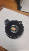 Oval cabochon Ethiopian opal gemstone with visible vibrant colors, placed inside a black container.