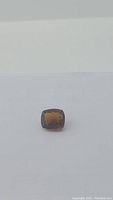 Image showing the 20.55ct cushion cut Madeira citrine gemstone with a deep cognac orange color on a white background.