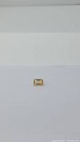 Top-down view showing rectangular shape and depth of bright golden citrine gemstone on white background.