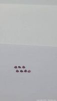 Seven loose pear-shaped red rubies on white background