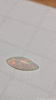 Marquise opal cabochon on white grid paper, showing overall shape and color play