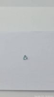Small, light blue trillion cut aquamarine gemstone on white background