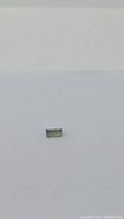 Natural bright green baguette cut tourmaline gemstone shown against white background.