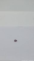 Single pear-shaped cherry red garnet cabochon gemstone on white background