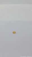 Oval cut natural golden yellow sapphire gemstone displayed on a white surface, showing size and color.