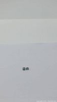 Photo showing two small natural olive green sapphires on a white background, octagon cut, appearing approx 4x4mm each.