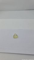 Natural lemon citrine gemstone placed on white background, showing bright, transparent yellow color and trillion shape.