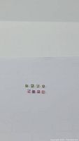 Top view of ten square cut natural tourmaline gemstones in green and pink shades arranged in two rows on a plain white background.