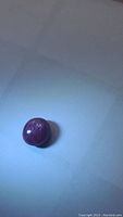 Top-down photo showing the polished cabochon star ruby with visible color and star effect under lighting.