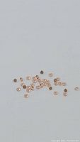 Multiple small orange-pink padparadcha sapphires scattered on a white background showing overall quantity and size.