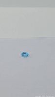 Oval cut, vibrant lagoon blue Swiss Blue Topaz gemstone on white background, showing top view with bright color and clarity