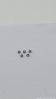 Top view showing five small round cut teal blue-green sapphires arranged in a loose round cluster on a white background.