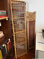 Four-panel bamboo screen with an open bamboo lattice design leaning against a bookshelf.