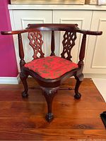 Front view of low height child-sized corner chair showing the full piece with carved wooden backrest and red cushion.