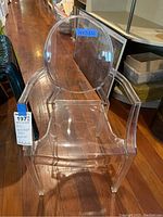 Full view of the transparent child-sized Lou Lou Ghost Chair showing its armrests, rounded backrest and overall design.